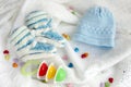 Knitted newborn baby booties and hat with colorful rattle on crocheted blanket white background with colorful hearts Royalty Free Stock Photo