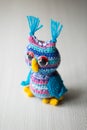 Knitted owl made of multicolored threads on a white background.