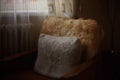 Knitted pillow and fur cape on a chair in the living room by the window Royalty Free Stock Photo