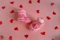 Knitted pink booties baby socks on pink background with hearts Royalty Free Stock Photo