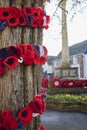 Knitted Poppies Around Tree For Remembrance Day With War Memorial And Poppy Wreaths In Background Royalty Free Stock Photo