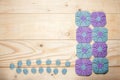 Knitted purple square napkins with exquisite pattern on background of light table made of wooden boards close up with place for