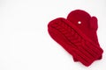 A knitted red mitten with white snowflake in the shape of a heart on a white background isolated. Concept of Christmas winter