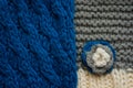 Knitted scarf pattern. Blue and gery threads. Small knitted flower on a scarf