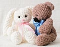 knitted teddy bear and rabbit sitting and talking on a sofa. hand made kids gifts, toys made of puffy thread. hobby and