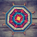 Knitted tibetan mandala from threads on wooden background