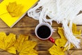 Knitted white scarf, book, cup of coffee and autumn maple leaves on wooden table. Top view. Autumn cozy concept Royalty Free Stock Photo