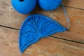 Knitted wool semicircular blue cloth and needles on wooden table