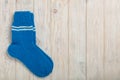 Knitted wool socks blue color on light wooden background.