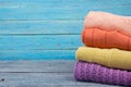 Knitted wool sweaters. Pile of knitted summer clothes on wooden background, sweaters, knitwear, space for text Royalty Free Stock Photo