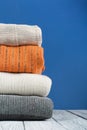 Knitted wool sweaters. Pile of knitted winter, autumn clothes on blue, wooden background, sweaters, knitwear, space for text Royalty Free Stock Photo