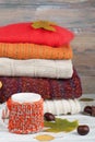 Knitted wool sweaters. Pile of knitted winter, autumn clothes on red, wooden background, sweaters, knitwear, ball, cup Royalty Free Stock Photo