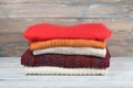 Knitted wool sweaters. Pile of knitted winter clothes on wooden background, sweaters, knitwear, space for text. Royalty Free Stock Photo