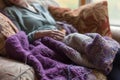 knitter resting with a halffinished purple woolen shawl on their lap