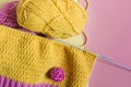 Knitting accessories skeins of yarn knitting needles and knitted blanks on a pink background needlework on a background