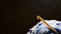 Knitting, hobbies, needlework. Close-up crochet hook stands in blue yarn against a dark background. Royalty Free Stock Photo