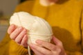 Knitting hobby.Skeins of yarn beige colour in hands in a in a mustard wool sweater.Wool yarn in beige.Hobby and Royalty Free Stock Photo