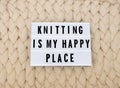 KNITTING IS MY HAPPY PLACE word on lightbox on knit background. Cozy compozition. Knit WOOL background. Royalty Free Stock Photo