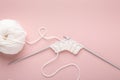 Knitting project in progress. White knitting wool and knitting needles on pastel pink background. Female hobby knitting Royalty Free Stock Photo