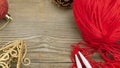 Knitting sticks red yarn and christmas decoration on old textured wooden background. Horizontal banner with copy space