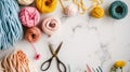 Knitting yarn balls in shades of pink, yellow, and blue, with scissors and hooks on a marble background