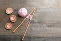 Knitting yarn with needles and candles on wooden table Royalty Free Stock Photo