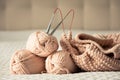 Knitting yarn, needles, chunky sweater. Cozy homely atmosphere. Yarn in warm colors of peach, beige. Knitting as a hobby.