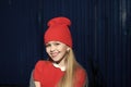 Knitwear. Child smiling with long blond hair outdoor, beauty. Small girl smile in red hat, fashion. Kid fashion trend