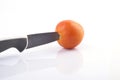 A knive cutting a tomato on white background