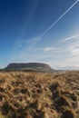 Knocknarea mountain in county Sligo, Ireland. Yellow grass and blue sky with airplane trail leading to the mountain.