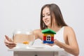 She knocks on the wall of the aquarium with goldfish and the other hand holding a toy house Royalty Free Stock Photo