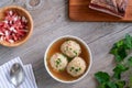 Knodel or canederli soup in a bowl with speck and parsley, top view