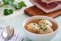 Knodel soup in a bowl with speck and parsley