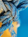 Knot made of blue twisted rope in the grains of sand, extreme close up