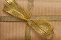 Knotted bow made of golden silk ribbon on brown kraft paper background Royalty Free Stock Photo