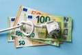 Knotted power cable with electric plug on 50 and 100 euro banknotes over blue background. Concept of rising energy costs in Europe