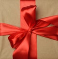 Knotted red silk ribbon on brown kraft paper background, festive backdrop Royalty Free Stock Photo