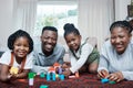 They know how to have fun as a family. Portrait of a happy family playing with wooden blocks together at home. Royalty Free Stock Photo