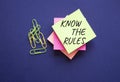 Know the rules symbol. Yellow steaky note with paper clips with words Know the rules. Beautiful deep blue background. Business and