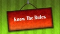 KNOW THE RULES text on hanging orange board. Green striped wallpaper background.