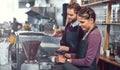 The know their way around a coffee machine. two young baristas operating a coffee machine together at a cafe.