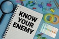 Know Your Enemy text with magnifying glass on blue background Royalty Free Stock Photo