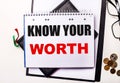 KNOW YOUR WORTH is written on white paper next to diaries, glasses and coins Royalty Free Stock Photo