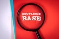 Knowledge base. Search and research concept. Magnifying glass on a red background