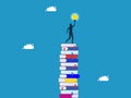 knowledge creates opportunities and wisdom for creative thinkers. Businessman on a high stack of books with a light bulb