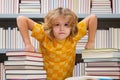 Knowledge day. Little student boy reading book at school. Kid doing homework, sitting at table by books, in library. Royalty Free Stock Photo