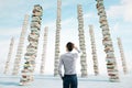 Knowledge and education concept with man back view looking on high stacks of books on abstract concrete surface and blue sky Royalty Free Stock Photo