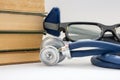 Knowledge, education, medicine and medical practice. Stack of books lies near stethoscope, neurological rubber hammer and points o Royalty Free Stock Photo