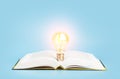 Knowledge study learning concept. Open book with a glowing light bulb on a blue background. Research, reading and study Royalty Free Stock Photo