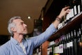 He knows a good vintage when he sees one. a handsome mature man buying wine at a grocery store. Royalty Free Stock Photo